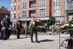 Na zdjęciu młody żołnierz składający kwiaty przed pomnikiem.