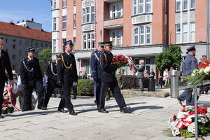 Na zdjęciu przedstawiciele służb mundurowych składający kwiaty przed pomnikiem.