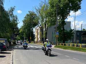 Na zdjęciu dwóch policjantów jadących na motocyklach służbowych, za nimi poruszający się motocykliści.