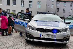 Na zdjęciu radiowóz policyjny, obok policjanci i dzieci.