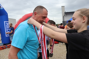 Na zdjęciu kobieta zakłada medal mężczyźnie, który ukończył bieg.