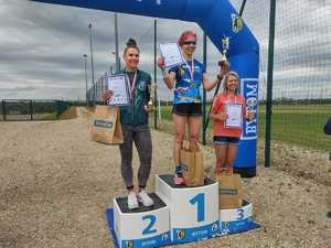 Na zdjęciu trzy osoby, medaliści stojący na podium.