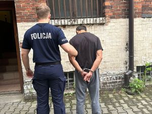 Na zdjęciu policjant trzymający mężczyznę w kajdankach