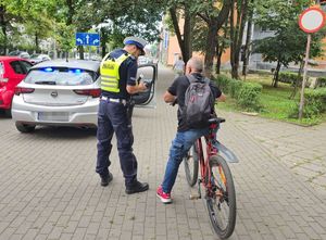 Na zdjęciu widzimy policjanta stojącego przy rowerzyście