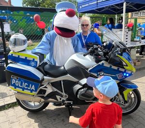 Na zdjęciu Sznupek, kobieta i dziecko przy motocyklu policyjnym.