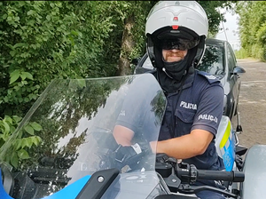 Na zdjęciu policjant w kasku, siedzący na motocyklu służbowym.