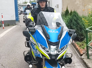 Na zdjęciu policjant w kasku, jadący na motocyklu służbowym.