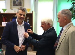 Na zdjęciu prezydent miasta Bytomia, obok dwaj mężczyźni, jeden z nich przypina mu medal.