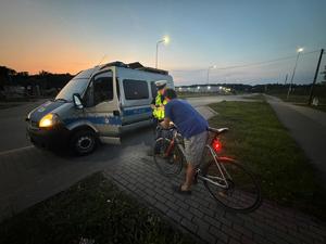 Na zdjęciu policjant, radiowóz i rowerzysta.