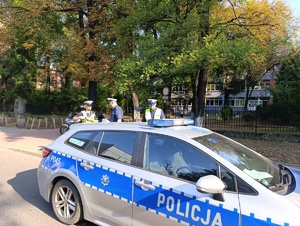 Na zdjęciu radiowóz i policjanci bytomskiej drogówki przed budynkiem szkoły.