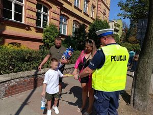 Na zdjęciu policjanci bytomskiej drogówki przekazujący pierwszoklasiście odblaskową opaskę.