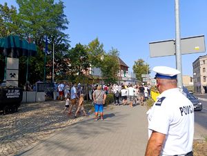 Na zdjęciu policjant i zgromadzone osoby.