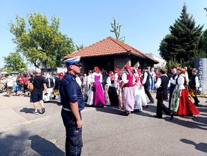 Na zdjęciu policjant oraz maszerujące osoby.