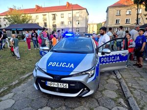 Na zdjęciu radiowóz policyjny i wchodzące do niego osoby.