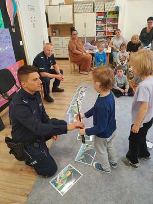 Na zdjęciu policjant pokazujący dzieciom wyposażenie.