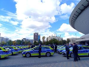 Na zdjęciu umundurowani policjanci stojący przy radiowozach służbowych