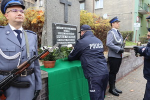 warta honorowa oraz komendant składający kwiaty przy tablicy upamiętniającej zamordowanego policjanta