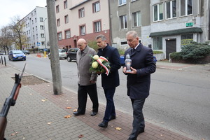 przedstawiciele władz samorządowych i ojciec zmarłego policjanta niosący kwiaty i znicz