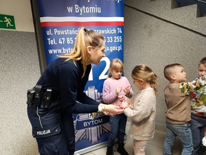 Na zdjęciu policjantka rozdająca dzieciom białoczerwone lizaki choinkowe.