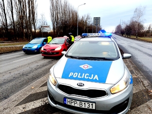 Na zdjęciu radiowóz policyjny, mundurowi stojący na jezdni i prowadzący badania trzeźwości nadjeżdżających kierujących.