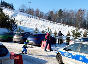 na zdjęciu policjant, radiowóz i stok narciarski pokryty śniegiem