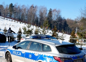 na zdjęciu policjant, radiowóz i stok narciarski pokryty śniegiem