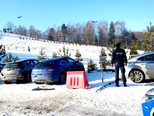 na zdjęciu policjant obserwujący stok narciarski pokryty śniegiem