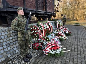 na zdjęciu żołnierz stojący przy pomniku obok niego złożone przed pomnikiem kwiaty