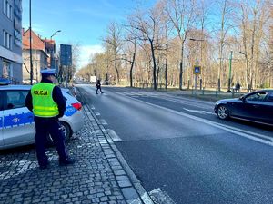 na zdjęciu policjant obserwujący przejście dla pieszych