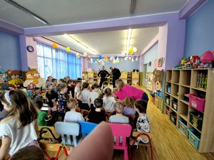 na zdjęciu przedszkolaki, przed nimi dwóch policjantów