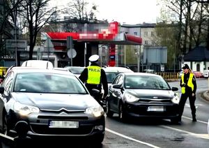 na zdjęciu policjanci drogówki stojący na jezdni przy samochodach, w trakcie badań trzeźwości
