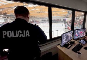 na zdjęciu policjant monitorujący lodowisku, obok niego ekrany monitorujące