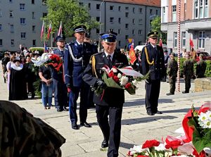 na zdjęciu przedstawiciele służb mundurowych z kwiatami