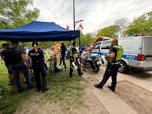 na zdjęciu policjanci przy stoisku policyjnym, radiowóz, motocykl służbowy oraz zgromadzone osoby