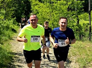 na zdjęciu widzimy dwóch mężczyzn z uniesionymi do góry kciukami w trakcie biegu, za nim kolejne biegnące osoby