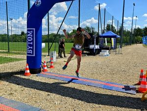 na zdjęciu mężczyzna w podskoku mijający linię mety