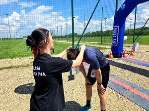 na zdjęciu kobieta zakłada mężczyźnie na szyję medal