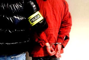 na zdjęciu dłonie zatrzymanego w kajdankach obok nieumundurowany policjant