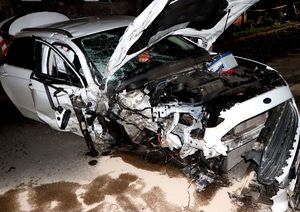 na zdjęciu uszkodzony samochód białego koloru, z rozbitym prawym przednim narożem, pozbawiony koła, z rozbitą przednią szybą czołową.