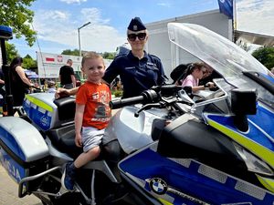 na zdjęciu chłopiec na motocyklu, obok niego policjantka