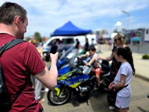 na zdjęciu mężczyzna robiący zdjęcie dziecku siedzącemu na motocyklu policyjnym