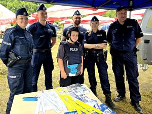 na zdjęciu dwie policjantki i trzej policjanci, przy nich chłopiec w kamizelce i kasku policyjnym,