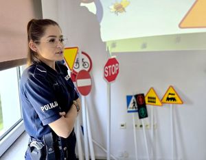 na zdjęciu policjantka , za nią znaki drogowe