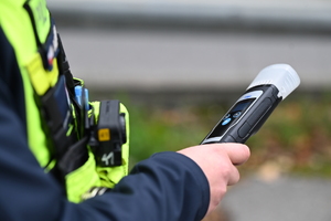na zdjęciu policjant trzymający w dłoni urządzenie do badania stanu trzeźwości