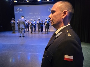 na zdjęciu profil policjanta, obok niego scena na której gra orkiestra policyjna