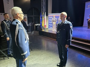 Na zdjęciu dwóch stojących naprzeciwko siebie policjantów, za nimi scena.