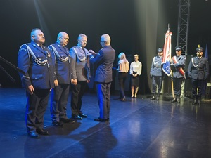 komendant wojewódzki i trzech policjantów w trakcie odznaczeń na scenie