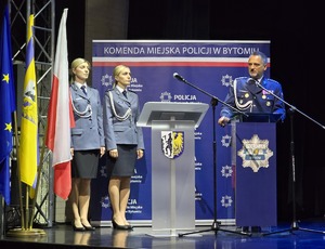 Michał Szczęśniak przy mównicy, obok dwie policjantki