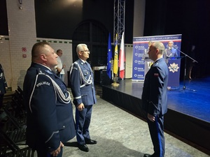 Na zdjęciu dwóch stojących naprzeciwko siebie policjantów, obok kolejny za nimi scena