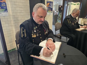 Na zdjęciu mundurowy w trakcie wpisywania do pamiątkowej księgi
